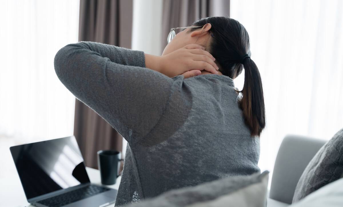 Überlastete junge Dame massiert den Nacken und fühlt sich durch sitzende Arbeit verletzt